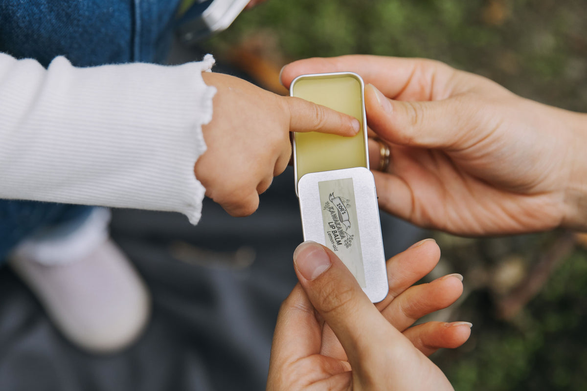 Person applying Zoe's Kawakawa 12ml tin to a child's hand outdoors